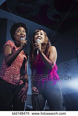 Friends singing karaoke in nightclub View Large Photo Image Stock Photography - Friends singing karaoke in nightclub. Fotosearch