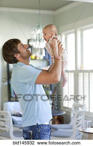 Stock Image - Happy Caucasian father holding baby daughter. Fotosearch