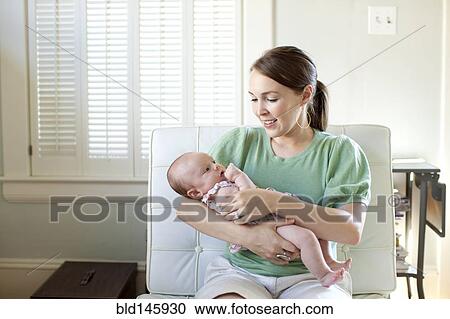Stock Image - Happy Caucasian mother holding baby daughter. Fotosearch