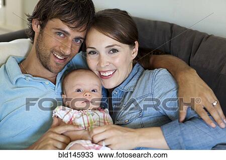 Happy Caucasian parents holding baby daughter View Large Photo Image Stock Image - Happy Caucasian parents holding baby daughter. Fotosearch