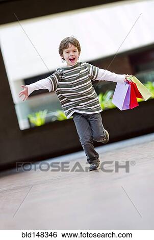 Stock Photograph - Hispanic boy running with shopping bags. Fotosearch