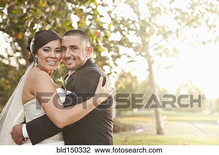 Stock Image - Hispanic bride and groom hugging. Fotosearch