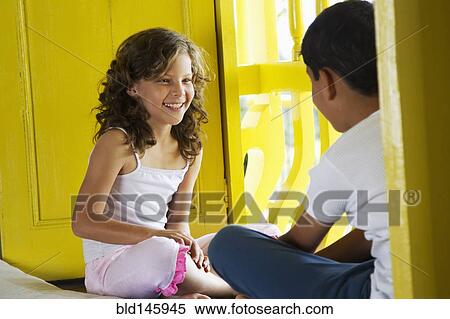 Stock Photography - Hispanic brother and sister looking out window. Fotosearch