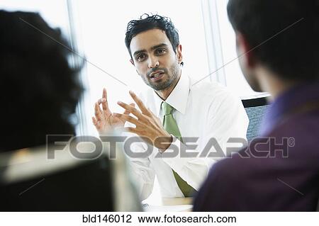 Stock Image - Hispanic business people working together in office. Fotosearch