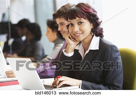 Stock Image - Hispanic business people working together in office. Fotosearch