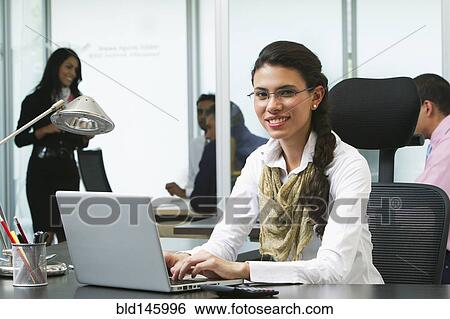 Stock Photograph - Hispanic businesswoman typing on laptop in office. Fotosearch