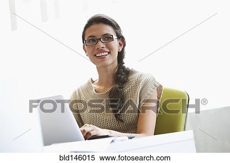 Stock Photography - Hispanic businesswoman typing on laptop at desk. Fotosearch