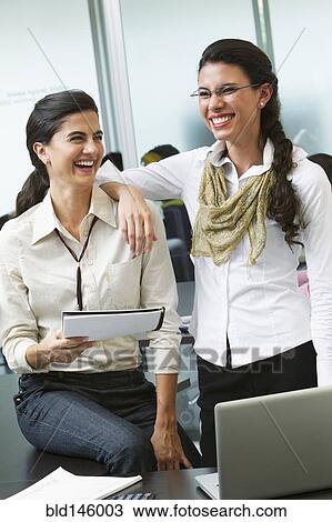 Stock Image - Hispanic businesswomen working together in office. Fotosearch