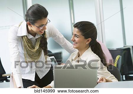 Stock Photo - Hispanic businesswomen working together in office. Fotosearch