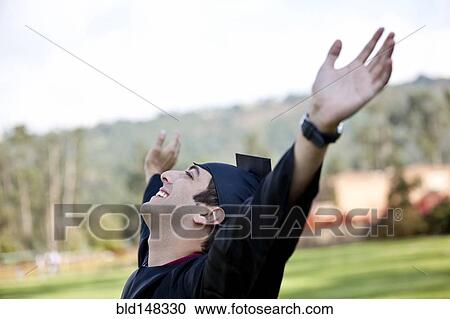 Stock Image - Hispanic college graduate cheering with arms raised. Fotosearch