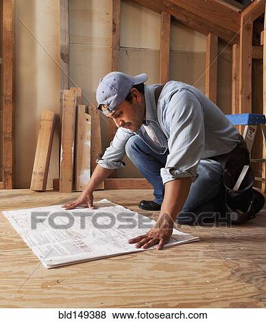 Stock Photo - Hispanic construction worker looking at blueprints. Fotosearch