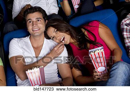Hispanic couple enjoying popcorn at movie theater View Large Photo Image Stock Image - Hispanic couple enjoying popcorn at movie theater. Fotosearch