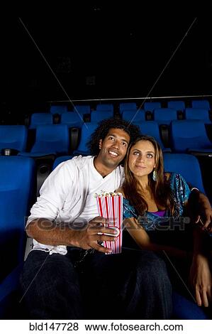 Hispanic couple enjoying popcorn in movie theater View Large Photo Image Stock Photo - Hispanic couple enjoying popcorn in movie theater. Fotosearch