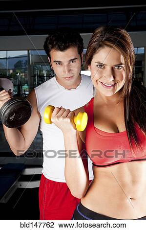 Hispanic couple lifting weights together in health club View Large Photo Image Stock Image - Hispanic couple lifting weights together in health club. Fotosearch