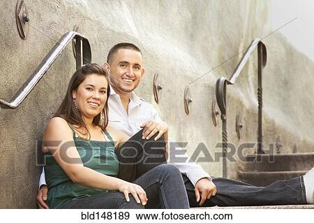 Stock Photo - Hispanic couple sitting on steps outdoors. Fotosearch