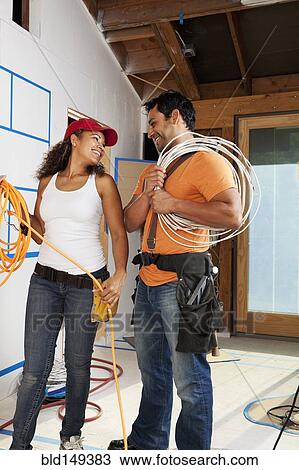 Stock Image - Hispanic couple wiring construction site. Fotosearch