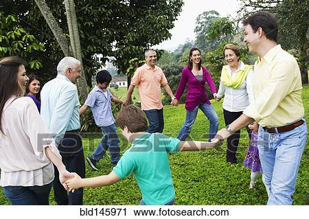 Stock Image - Hispanic family holding hands in a circle outdoors. Fotosearch