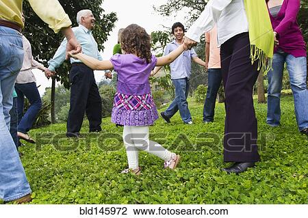 Stock Image - Hispanic family holding hands in a circle outdoors. Fotosearch