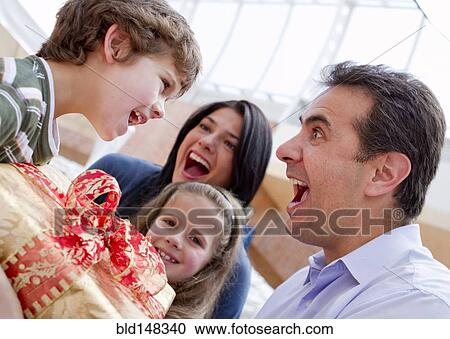 Stock Image - Hispanic father giving excited son birthday gift. Fotosearch