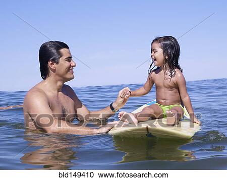 Hispanic father holding hands with daughter on surfboard View Large Photo Image Stock Image - Hispanic father holding hands with daughter on surfboard. Fotosearch