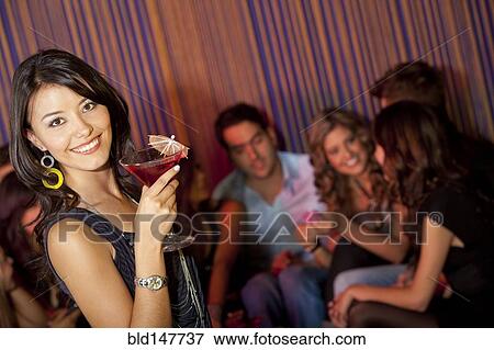 Stock Photo - Hispanic friends drinking cocktails in bar. Fotosearch