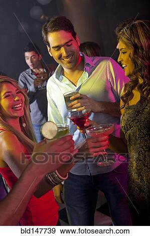 Stock Photo - Hispanic friends drinking cocktails in bar. Fotosearch