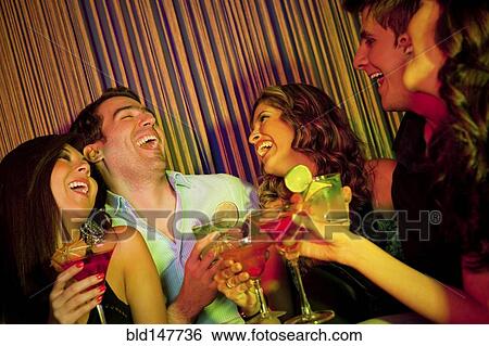 Stock Photograph - Hispanic friends drinking cocktails in bar. Fotosearch