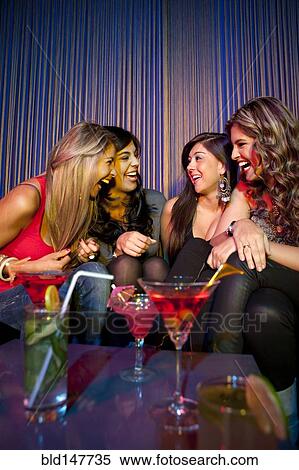 Stock Photography - Hispanic friends drinking cocktails in bar. Fotosearch