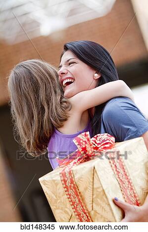 Stock Photography - Hispanic girl giving happy mother birthday gift. Fotosearch