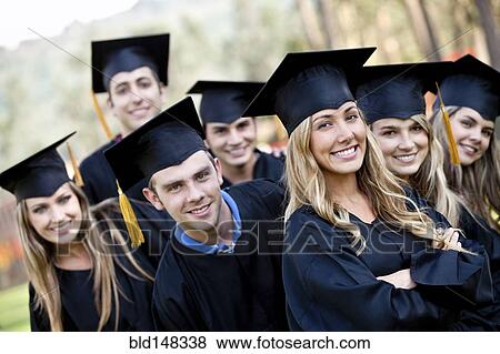 Stock Photo - Hispanic graduates in caps and gowns standing together. Fotosearch