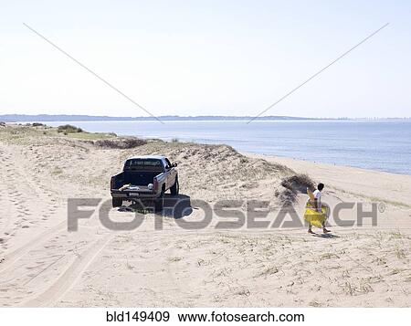 Hispanic man carrying lounge chair to beach View Large Photo Image Stock Photo - Hispanic man carrying lounge chair to beach. Fotosearch