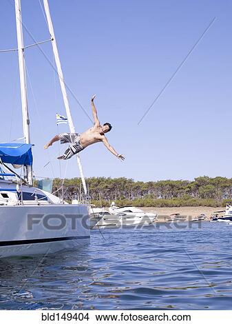 Hispanic man jumping into ocean from sailboat View Large Photo Image Picture - Hispanic man jumping into ocean from sailboat. Fotosearch