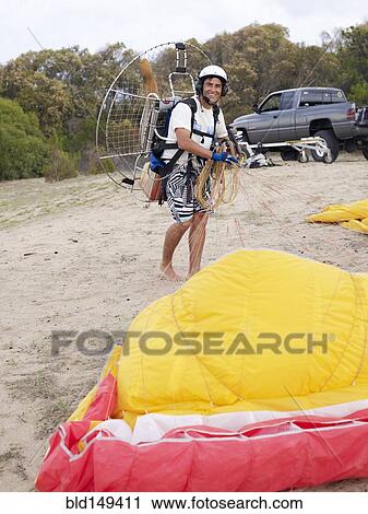 Stock Image - Hispanic man paragliding. Fotosearch