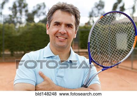 Hispanic man standing on tennis court with racquet View Large Photo Image Stock Photo - Hispanic man standing on tennis court with racquet. Fotosearch