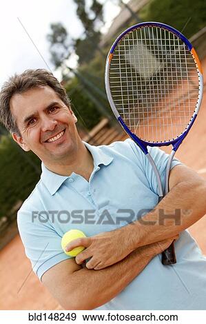 Stock Photo - Hispanic man standing on tennis court with racquet. Fotosearch