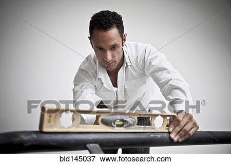 Hispanic man using level on railing View Large Photo Image Stock Photo - Hispanic man using level on railing. Fotosearch
