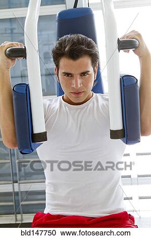 Stock Image - Hispanic man working out in health club. Fotosearch
