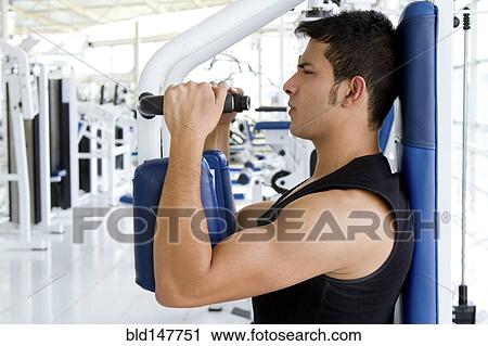 Stock Image - Hispanic man working out in health club. Fotosearch