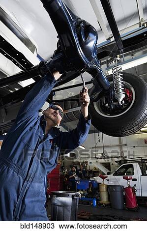 Stock Image - Hispanic mechanic working on car. Fotosearch