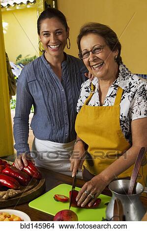 Picture - Hispanic mother and daughter cooking together. Fotosearch