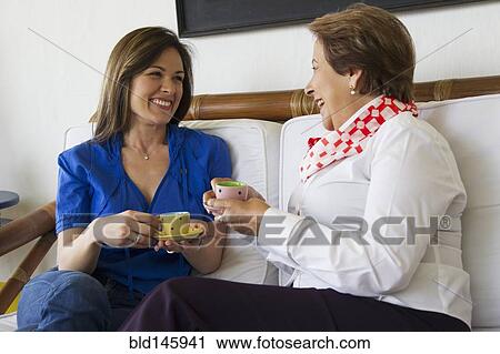 Stock Image - Hispanic mother and daughter drinking coffee together. Fotosearch