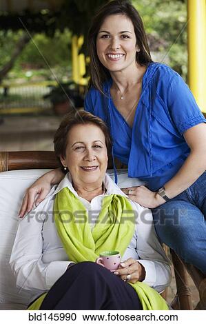 Stock Image - Hispanic mother and daughter sitting on porch. Fotosearch