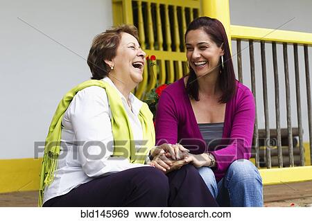 Stock Photo - Hispanic mother and daughter sitting on steps together. Fotosearch