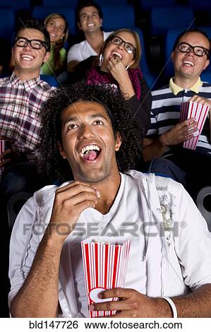 Stock Photograph - Hispanic people enjoying popcorn in movie theater. Fotosearch