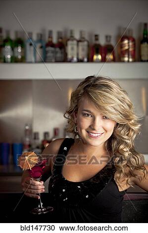 Stock Image - Hispanic woman drinking martini. Fotosearch