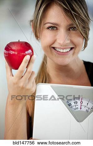 Hispanic woman holding apple and weighting scale View Large Photo Image Stock Photograph - Hispanic woman holding apple and weighting scale. Fotosearch
