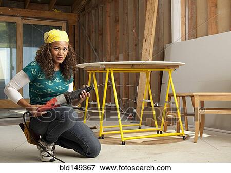 Stock Photo - Hispanic woman holding power tool. Fotosearch