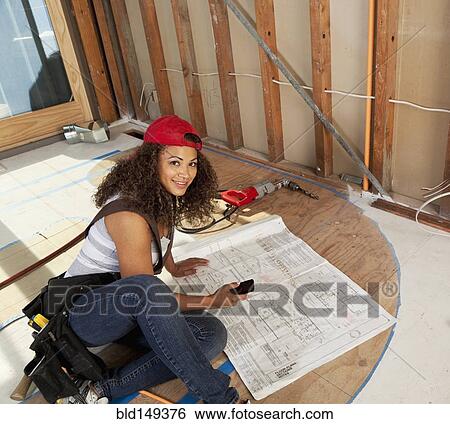 Stock Photograph - Hispanic woman looking at blueprints. Fotosearch