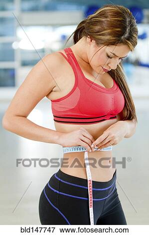 Stock Photo - Hispanic woman measuring waistline. Fotosearch
