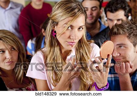 Stock Photo - Hispanic woman putting on makeup in classroom. Fotosearch